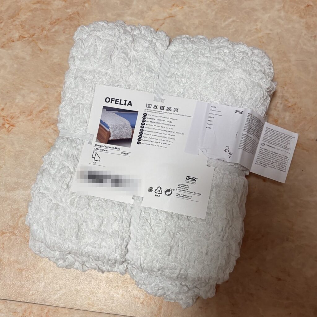 袋に入ったままのIKEAの白いベッドカバーOFELIA。ラベルに130×170cmの表示