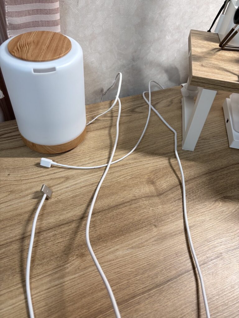 Before:木目の机の上に、白い充電ケーブルが何本も広がっている。左にライト