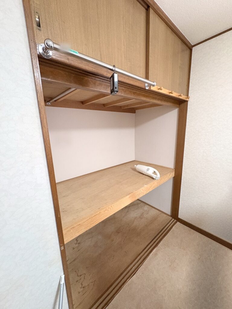 中の物を出したあとの押し入れ。上の段のふちに銀色のポールが付いていて、中段の板の上は空になっている