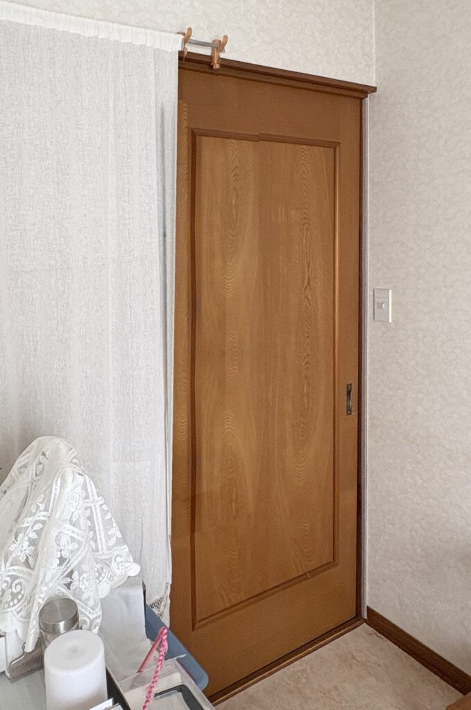 Before：茶色い木目の部屋の引き戸。左に白いカーテンがある