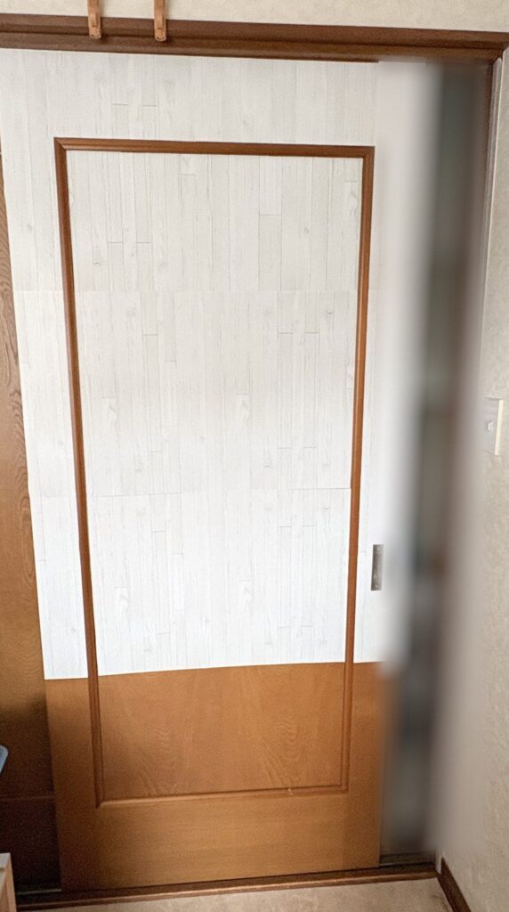 途中：部屋の引き戸の上のほうに、白木目のリメイクシートを貼ったところ。下のほうはまだ茶色