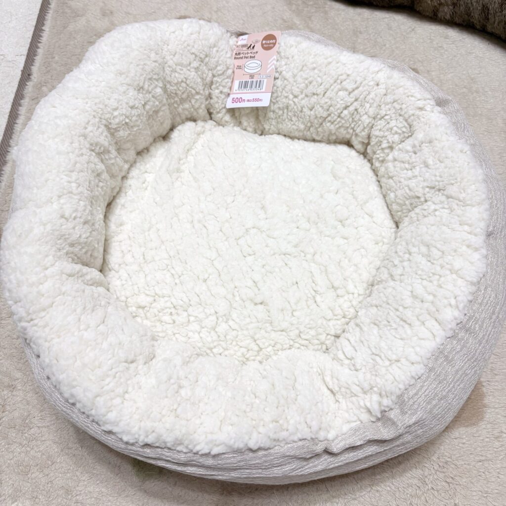 DAISOの丸形ペットベッド。白いもこもこの生地で、ふちはベージュ。値札が付いている