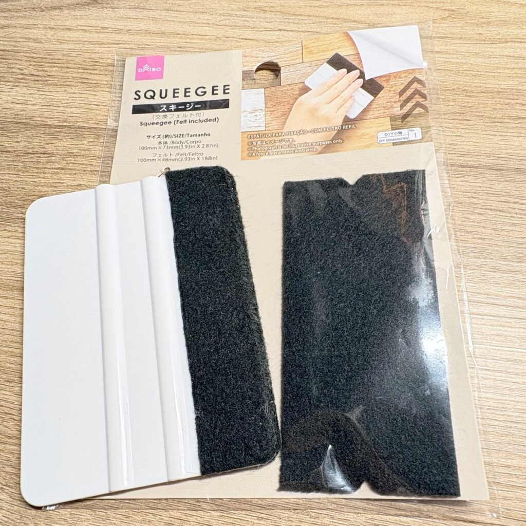 DAISOのスキージー（交換フェルト付）。白いヘラの片側に黒いフェルトが付いていて、交換用のフェルトも入っている